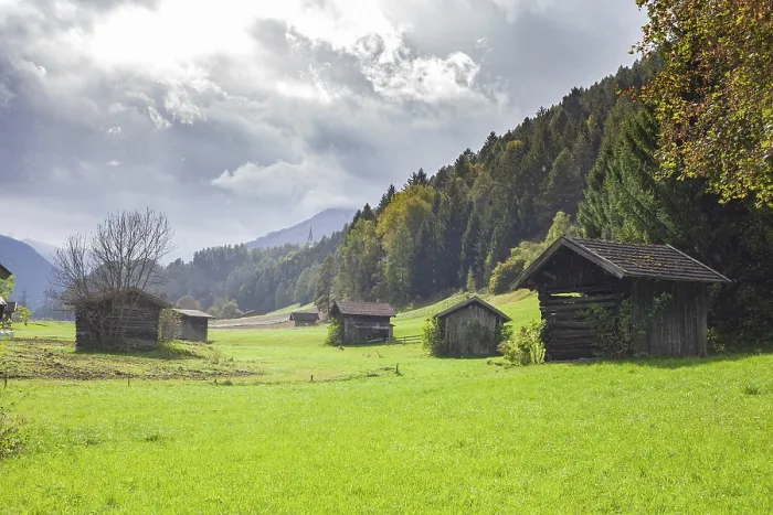 Framed Print : Pasture with haybars and mountains with dark clouds in the Stubai Valley between Telfes and Mieders