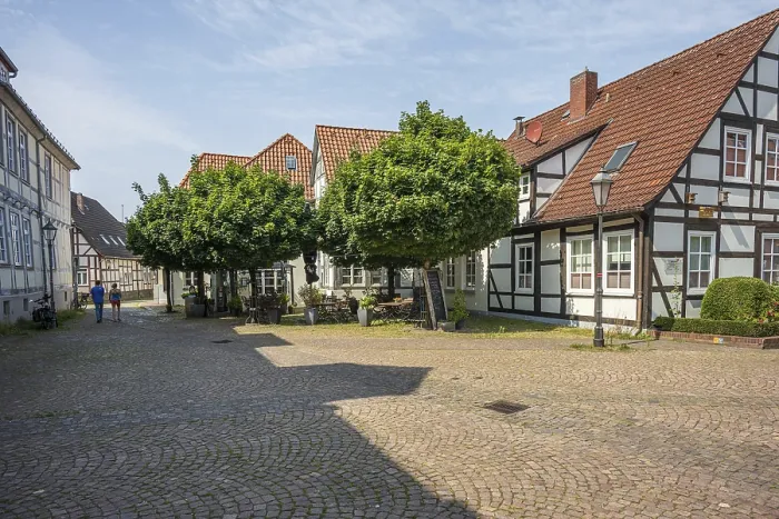 Framed Print : Paved courtyard with traditional half-timbered houses and trees