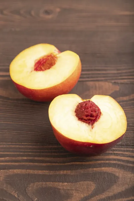 Framed Print : Peach Cut in half on brown wooden background Framed Print : Peach Cut in half on brown wooden background