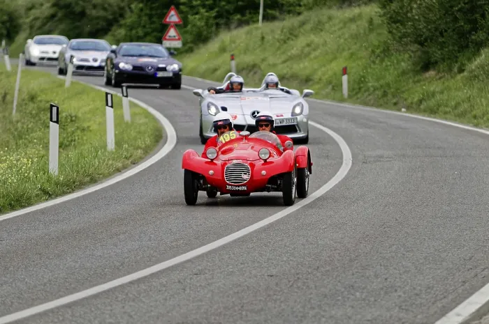 Framed Print : Two people with helmets in a red classic car on a country road