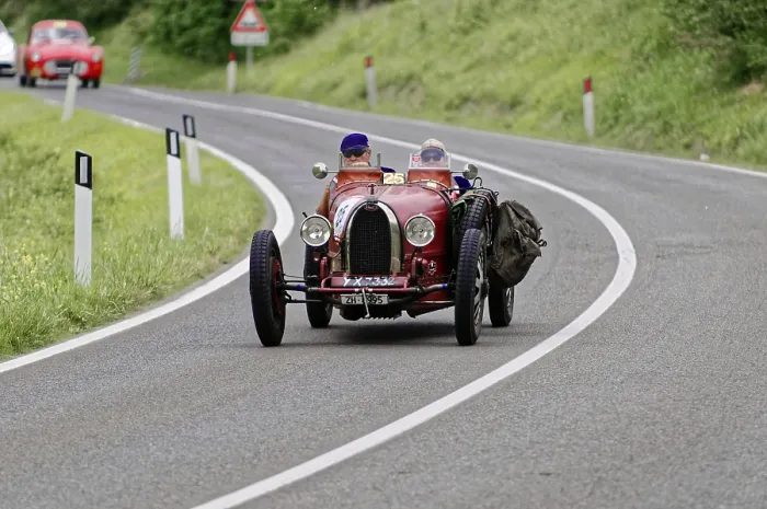 Framed Print : Two people with helmets in a red vintage car on a winding road