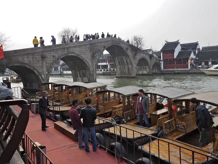 Framed Print : People on a stone bridge admire the wooden boats on the river in a historic city setting