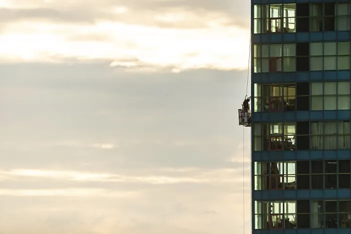 Framed Print : Person cleaning windows on a tall building against a cloudy sky in Toronto