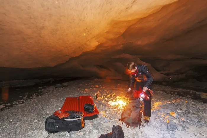 Framed Print : A person kneels by a campfire in a glacier cave