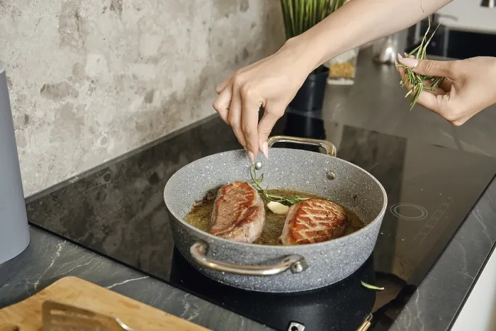 Framed Print : A person is preparing two pieces of duck breast in a frying pan