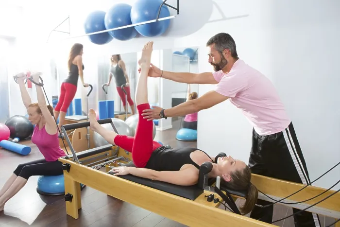 Framed Print : Pilates aerobic personal trainer instructor man in cadillac fitness woman exercise
