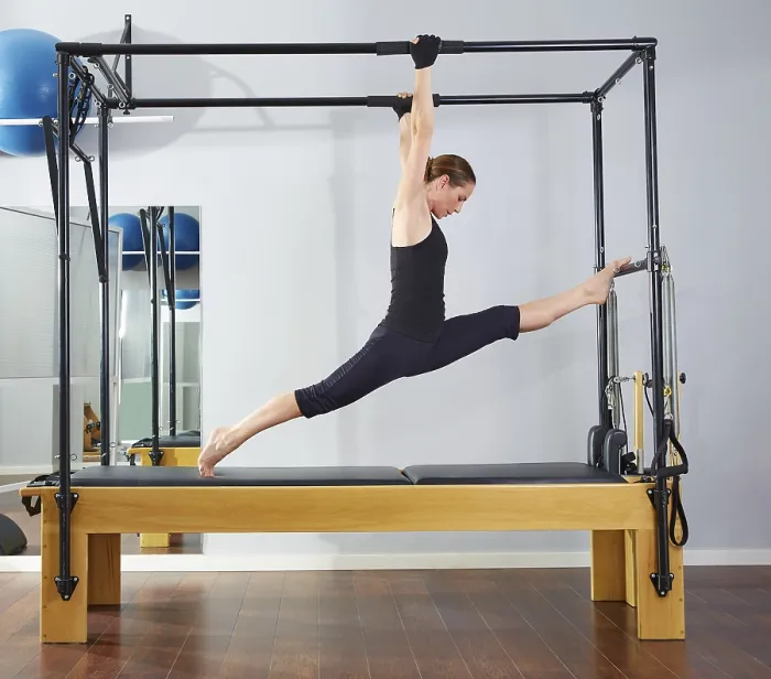 Framed Print : Pilates woman in cadillac legs split reformer exercise at gym