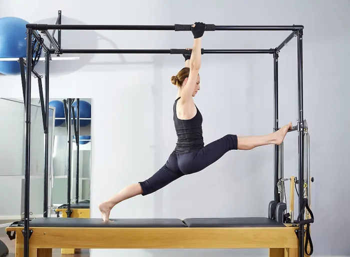 Framed Print : Pilates woman in cadillac legs split reformer exercise at gym