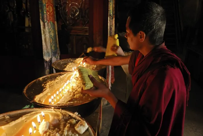 Framed Print : Pilgrim and Tibetan monks refilling the brass bow with yak butter