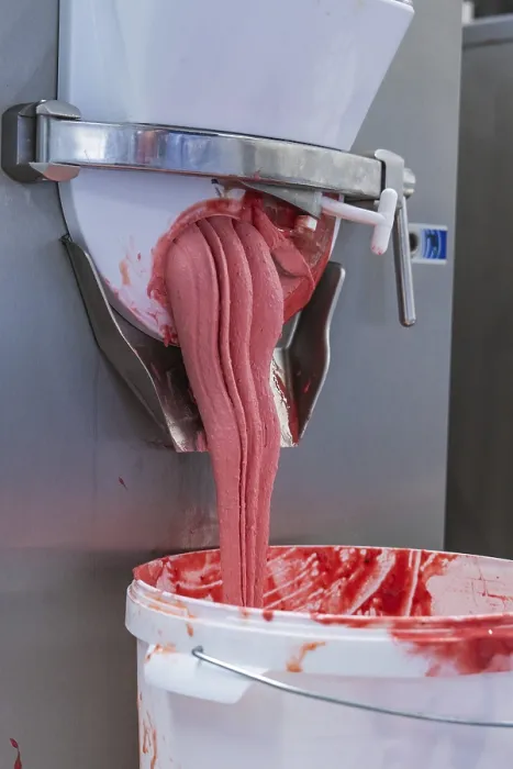 Framed Print : Pink-coloured ice cream mass flows viscously from a machine into a bucket