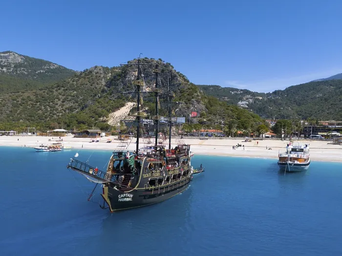 Framed Print : Pirate ship sails in front of a picturesque coastal landscape with mountains and clear blue water
