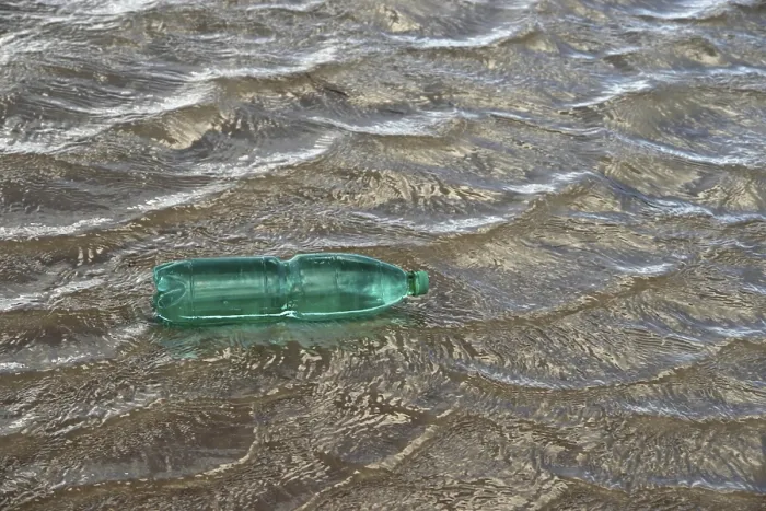 Framed Print : Pollution theme with a green plastic bottle floating on water surface Framed Print : Pollution theme with a green plastic bottle floating on water surface