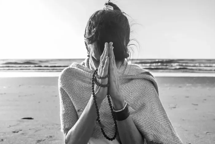 Framed Print : Portrait of a woman clasping hands while holding a japa mala at the beach