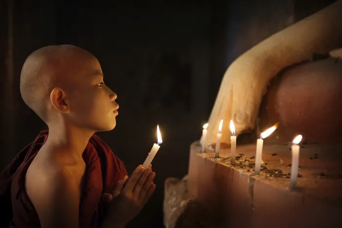 Framed Print : Portrait of young novice monk praying with candlelight inside a Buddhist temple