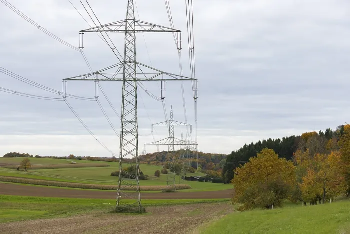 Framed Print : Power poles in a field under cloudy sky with autumn trees
