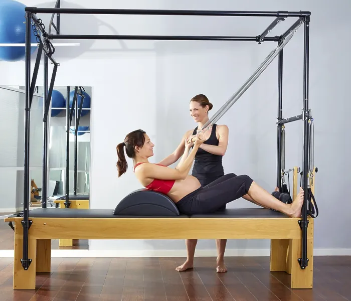 Framed Print : Pregnant woman pilates reformer roll up cadillac exercise with personal trainer