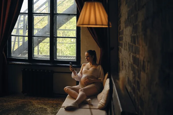 Framed Print : A pregnant woman sits comfortably on a couch at home