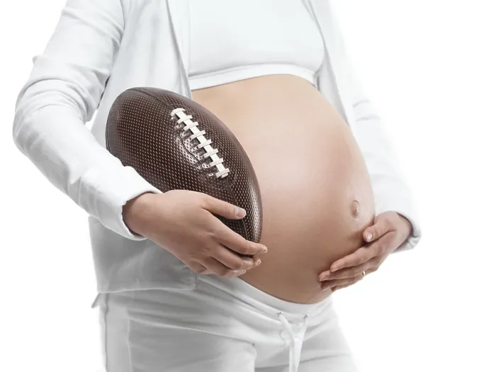 Framed Print : Pregnant young woman holding a football under her arm
