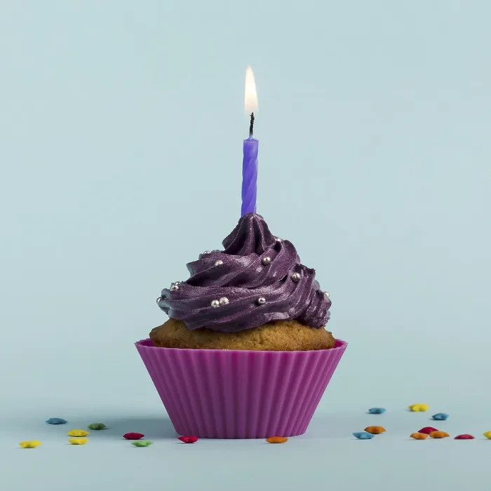 Framed Print : Purple burning candles decorative muffins with colorful star sprinkles against blue backdrop