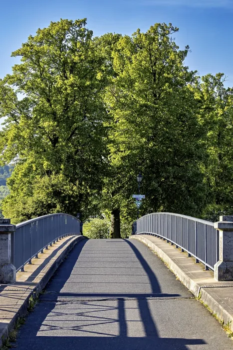 Framed Print : A quiet bridge with railings leads through green trees under a sunny blue sky