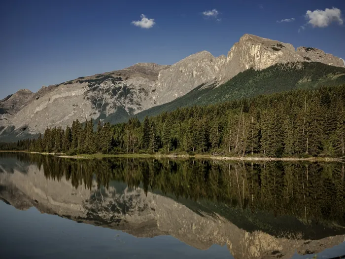 Framed Print : Quiet, reflective waters mirror the surrounding Canadian Rocky Mountains and forest near Canmore