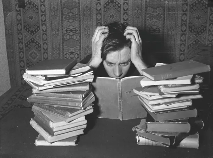 Framed Print : Reading in the 1940s. A young man with his study books in front of him looks as if he is studying hard