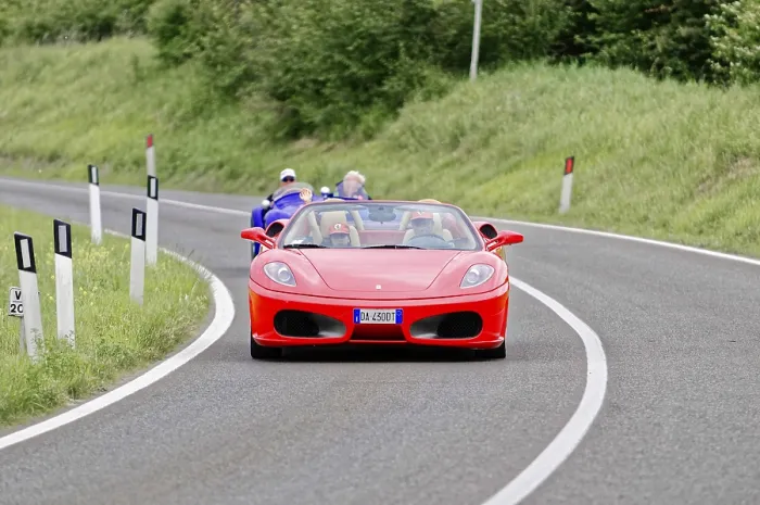 Framed Print : Red Ferrari convertible on winding road surrounded by green landscape