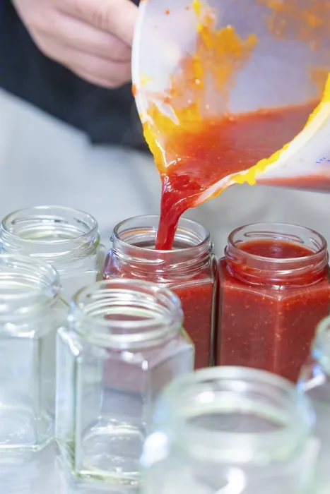 Framed Print : Red liquid is poured from a measuring cup into empty jars