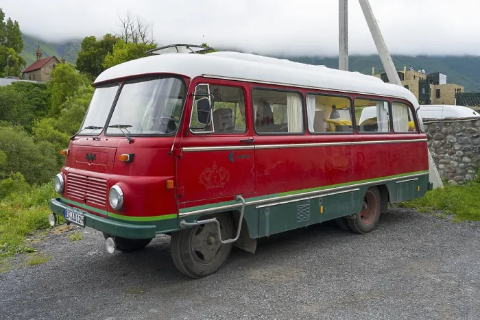 Framed Print : Red retro bus with green stripes on a road in a rural mountain landscape