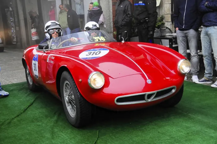 Framed Print : Red roadster with two helmeted drivers rolls across the green carpet at the rally