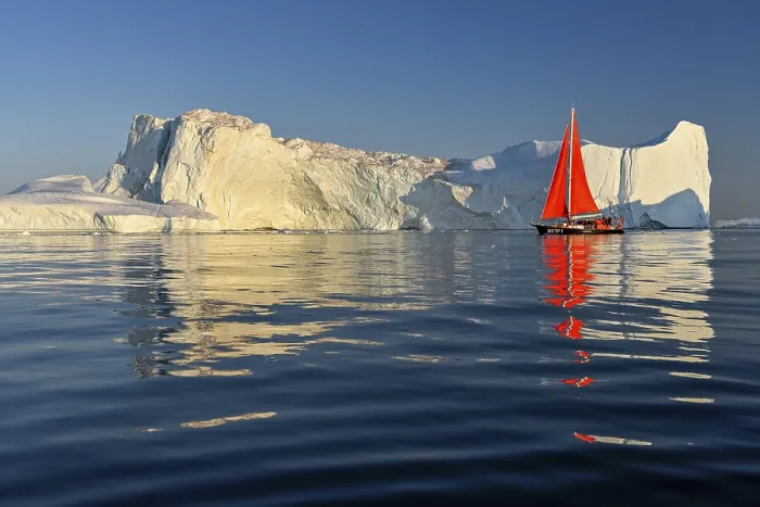 Framed Print : Red sailing boat in front of icebergs