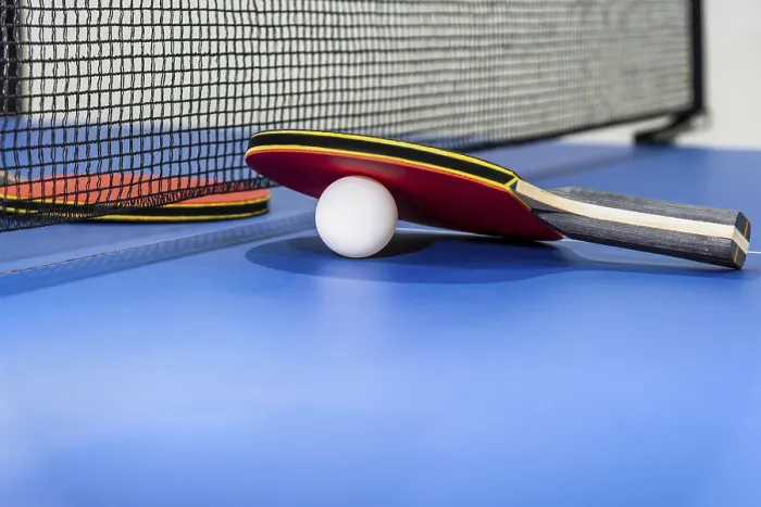 Framed Print : Red table tennis racket and a white ball on the blue ping pong table with a black net