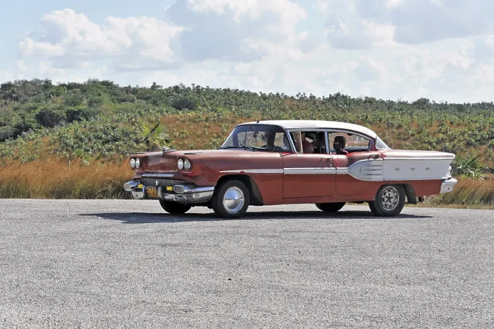 Framed Print : Red vintage car driving on a road through Cuban countryside