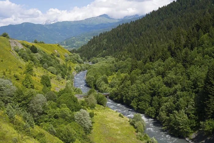 Framed Print : River flows through green mountains and forests with a peaceful summer atmosphere under cloudy skies