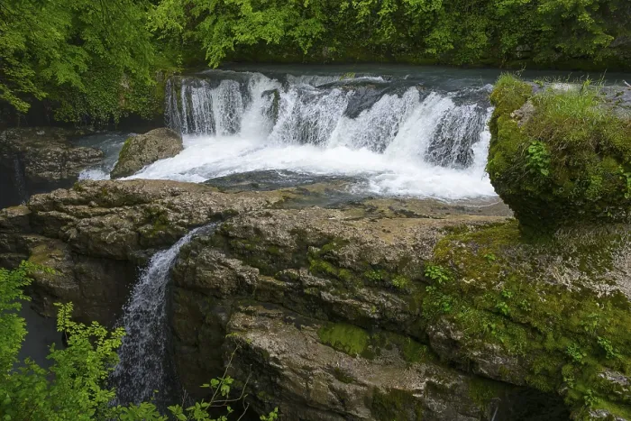 Framed Print : River waterfall with moss-covered rocks in a green forest