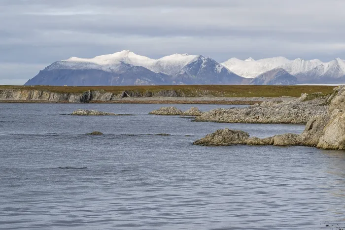 Framed Print : Rocks, coastal landscape, snowy mountains