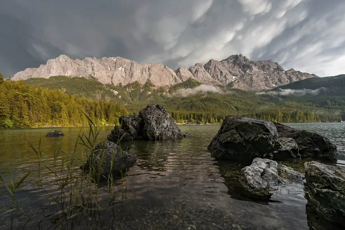 Framed Print : Rocks on the shore, Eibsee lake in front of Zugspitze massif with Zugspitze
