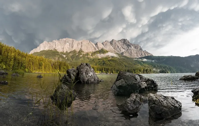 Framed Print : Rocks on the shore, Eibsee lake in front of Zugspitze massif with Zugspitze