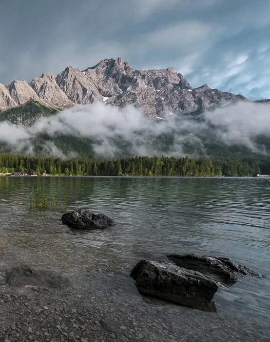 Framed Print : Rocks on the shore, Eibsee lake in front of Zugspitze massif with Zugspitze