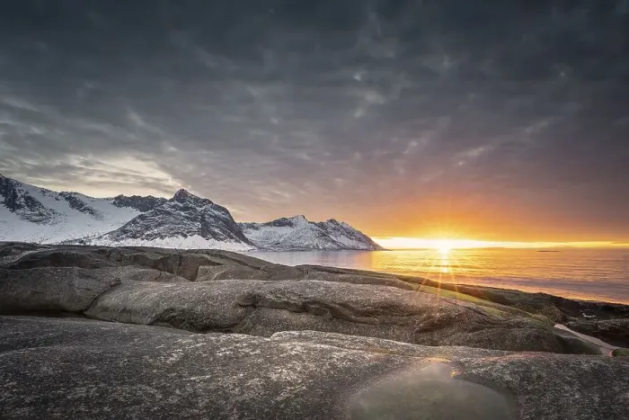 Framed Print : Rocky beach of Tungeneset, snow-covered mountain peaks in the warm sunlight above the sea Framed Print : Rocky beach of Tungeneset, snow-covered mountain peaks in the warm sunlight above the sea