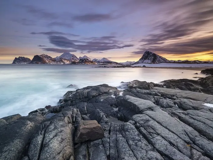 Framed Print : Rocky coast, snow-capped mountains in the background Framed Print : Rocky coast, snow-capped mountains in the background