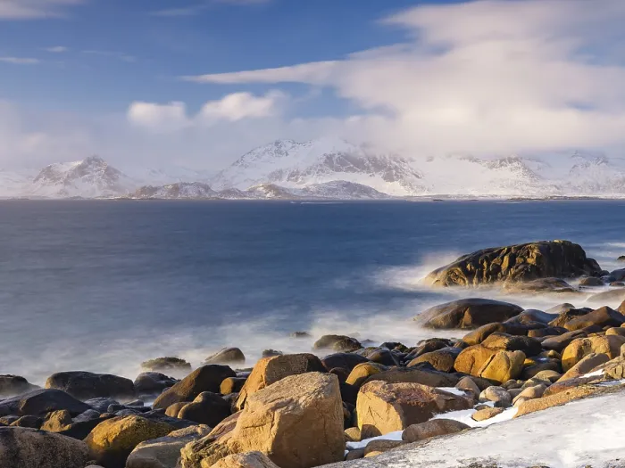 Framed Print : Rocky coast, snow-capped mountains in the background