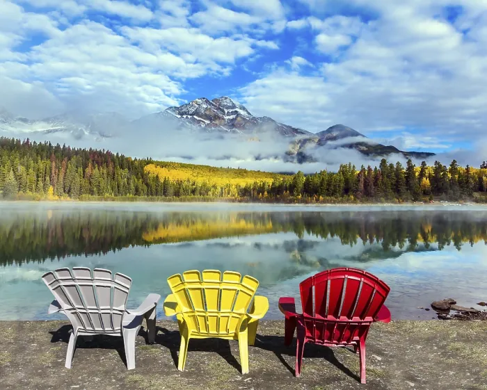 Framed Print : Rocky Mountains of Canada. Three comfortable multi-colored deck chairs stand by the Piramid lake