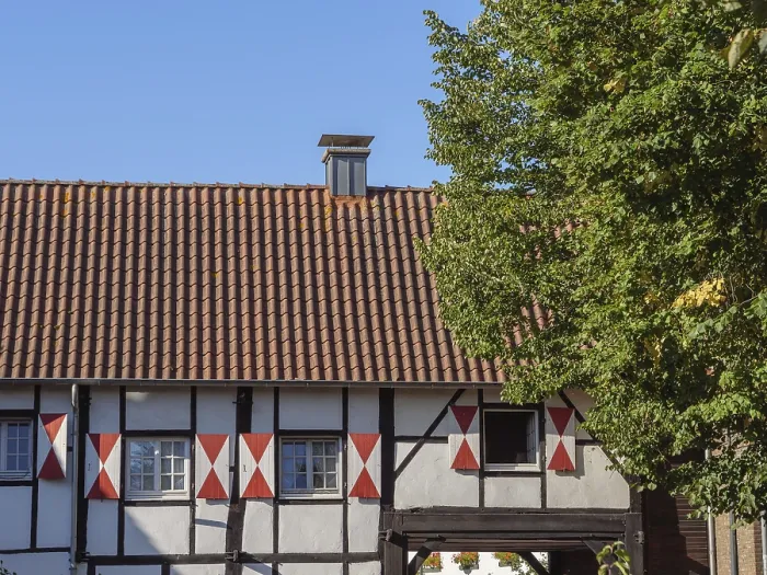 Framed Print : A rustic half-timbered house with red roof and trees in the background Framed Print : A rustic half-timbered house with red roof and trees in the background