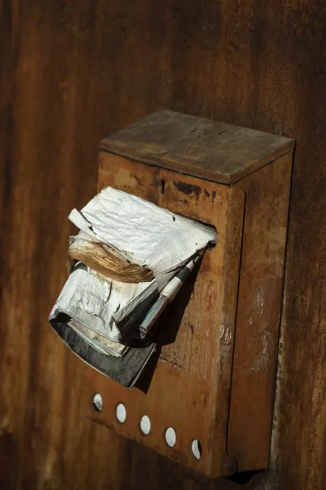 Framed Print : A rusty mailbox attached to a weathered wall is bursting with various papers and ads