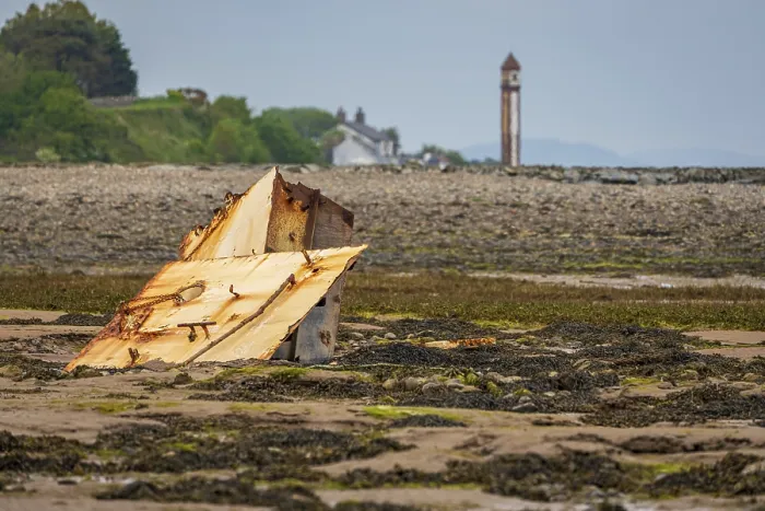 Framed Print : A rusty part of a shipwreck in the mud of the Walney Channel with the Rampside Lighthouse in the background