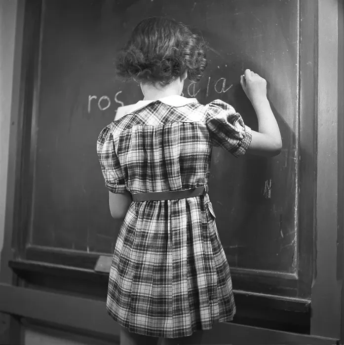 Framed Print : School in the 1940s. A girl in front of the classroom at the blackboard