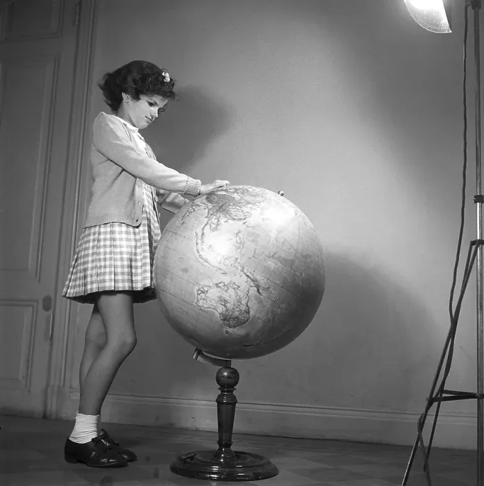 Framed Print : School in the 1940s. A girl in is very closely studying the details of a globe