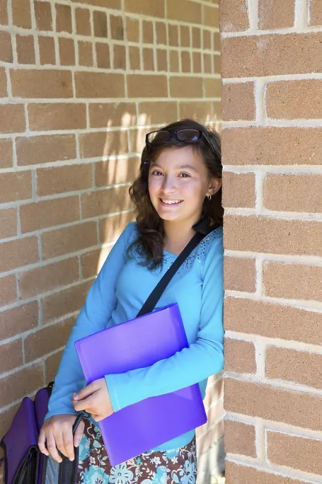 Framed Print : Schoolgirl teenager at school brick wall happy with folder and bag Framed Print : Schoolgirl teenager at school brick wall happy with folder and bag