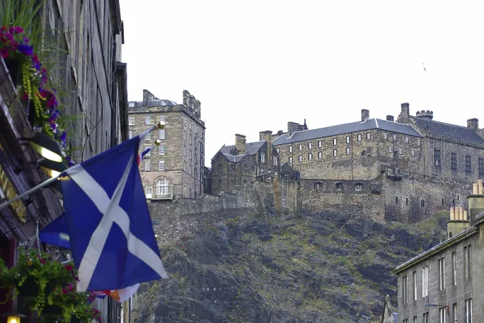 Framed Print : Scottish castle on a hill surrounded by buildings and a Scottish flag